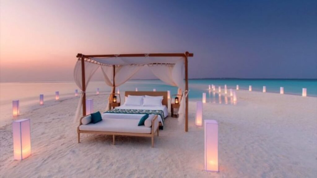 bed on the beach sand, beautiful lighting, showing hotels for romantic retreats  